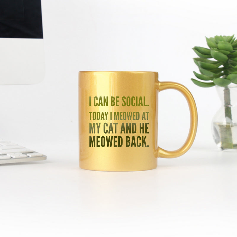 Ceramic mug with gold metallic coating featuring a playful cat-themed design and the phrase 'I Can Be Social Today I Meowed At My Cat And He Meowed Back'.